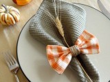 an orange bow as a napkin ring is a very cute and bright idea for a rustic wedding