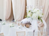 a refined neutral spring wedding reception with white blooms, feathers, touches of gold for a chic feel