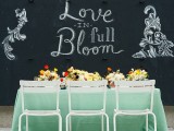 a bold spring wedding reception with a chalkboard wall, a mint tablecloth, bright blooms for centerpieces