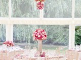 a chic indoor spring wedding reception with lush bright blooms over the tables and on them, pink tablecloths and pastel touches