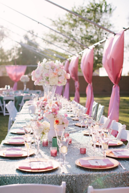 a colorful outdoor spring wedding reception with pink curtains, napkins, candleholders and tall centerpieces of blush blooms