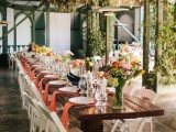 an indoor spring wedding reception with greenery over it, bright blooms and greenery, peachy napkins