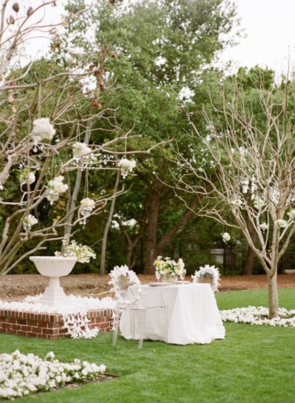 neutral and blooming spring reception space done with whte blooms on branches, blooms on the ground and blooms on the chairs