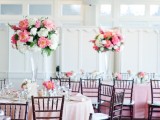 a romantic pink and blush wedding reception indoors, with blush and pink linens and blooms in tall vases
