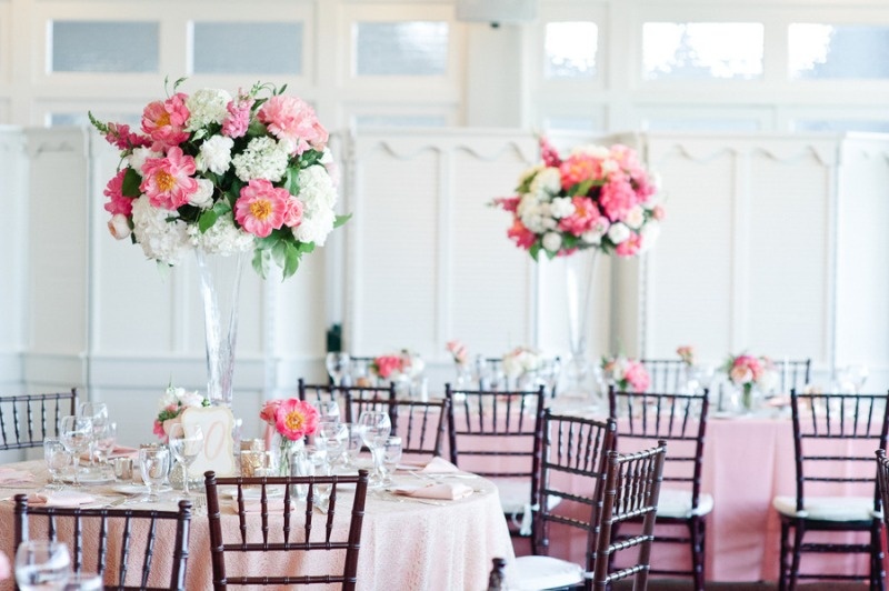 a romantic pink and blush wedding reception indoors, with blush and pink linens and blooms in tall vases