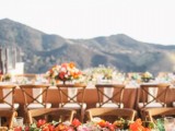a colorful outdoor wedding reception done with bold blooms and greenery, some candles and colorful glasses