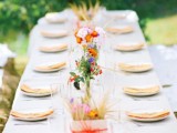 a colorful outdoor spring wedding reception with colorful buntings, bright blooms, neutral linens and a white base