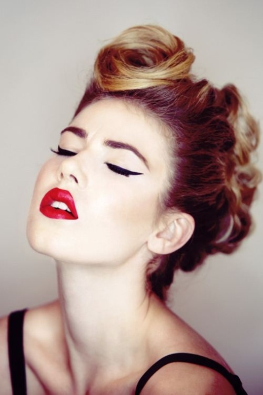 A retro inspired makeup with cat eyes and a bold red lip and a wavy updo