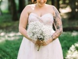 a strapless draped wedding ballgown with no sleeves lets us see a whole black ink sleeve on the bride’s arm