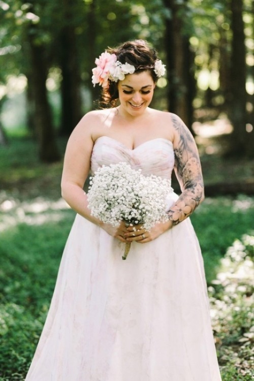 a strapless draped wedding ballgown with no sleeves lets us see a whole black ink sleeve on the bride's arm