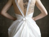an A-line wedding dress with straps on the open back that shows off the bride’s tattoos at their best
