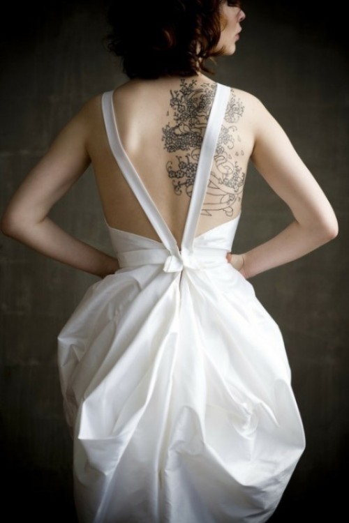 an A-line wedding dress with straps on the open back that shows off the bride's tattoos at their best