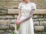 a beautiful wedding dress with a lace bodice and sleeves that show off the bride’s tattoo sleeve, a pleated skirt