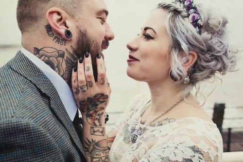 semi sheer lace on the bodice shows off the bride's tattoos, and her wrist and hand tattoos are seen very well