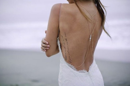 a lace fitting wedding dress with straps, chains and beads on the cutout back that shows off the tattoo on the back