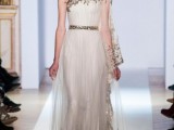 a fully pleated sheath one shoulder wedding dress with gold embroidery on the shoulder and rim, an embellished sash