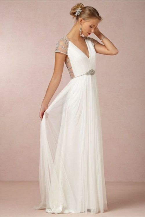 a Grecian pleated A-line wedding dress with a V-neckline, an open back, embellishments on the bodice, back and sleeves
