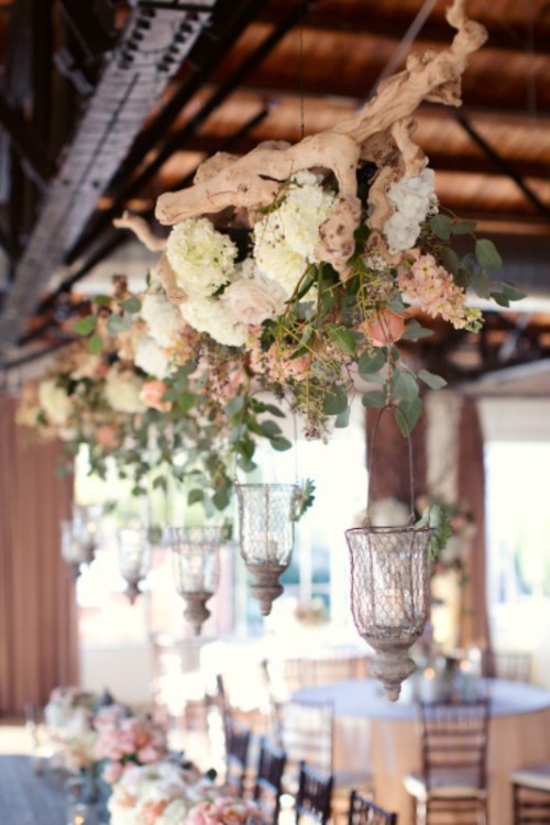 driftwood with eucalyptus and white hydrangeas with candle holders hanging down from it