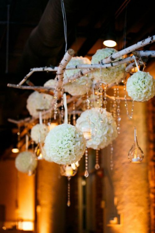 an overhead floral installation of brich branches, crystals hanging down, clear candleholders and some white floral orbs is wow