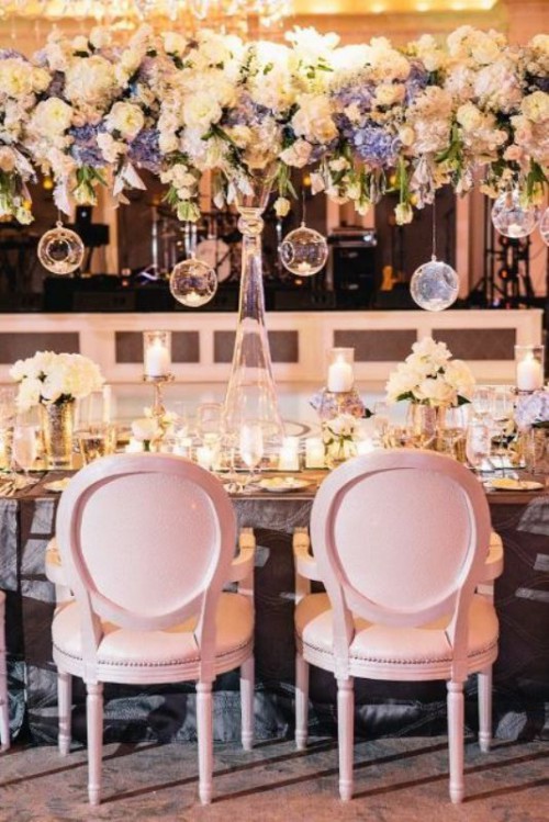 a neutral and pastel overhead floral decoration with some bulbs hanging down is romantic and beautiful