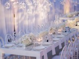 a lush white floral installation with candles hanging in clear candleholders from above