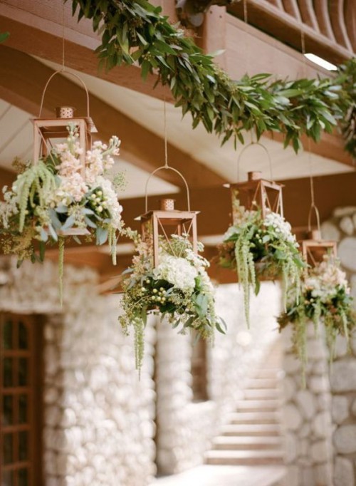 copper candle holders with white blooms and greenery plus a lush greenery garland over the reception