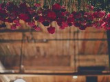 red carnations hanging down from overhead are a bright and chic idea to rock