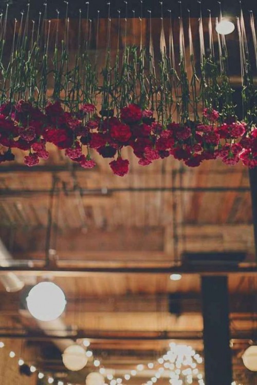 red carnations hanging down from overhead are a bright and chic idea to rock