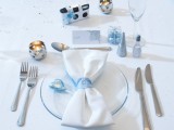 a beautiful silver and ice blue winter wedding place setting with a ice blue ornaments, an ice blue glass plate, ribbons and salt and pepper
