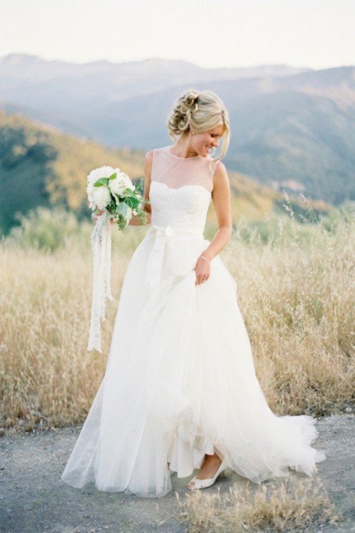 a modern wedding ballgown with an illusion bodice, no sleeves and a tulle skirt with a train is a cool and chic solution