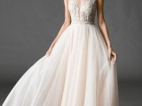a romantic illusion neckline A-line wedding dress with an embellished bodice and no sleeves and a layred skirt is a beautiful solution