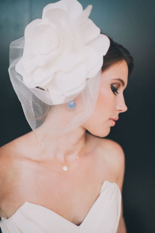 an oversized white flower headpiece with a small veil is a bold and cool idea for a modern bride, it combines two pieces in one
