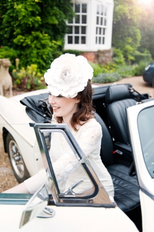 an oversized white fabric flower headpiece as a hat is a stylish and elegant idea for a vintage-inspired and refined bridal look