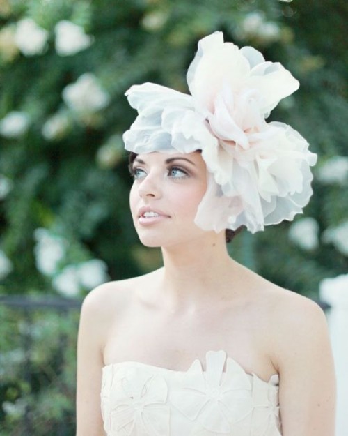 an oversized blush and white fabric bloom headpiece is a gorgeous statement for a bridal look, with a bit of fun