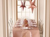 a pink tablecloth and gold, silver and rose gold stars over the table for decorating a cool glam wedding reception