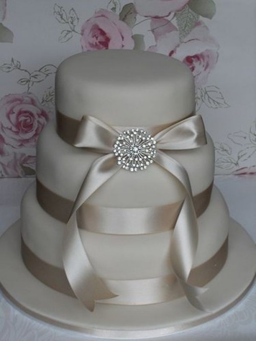 a neutral wedding cake with satin ribbons and a vintage brooch is a perfect idea for a vintage wedding