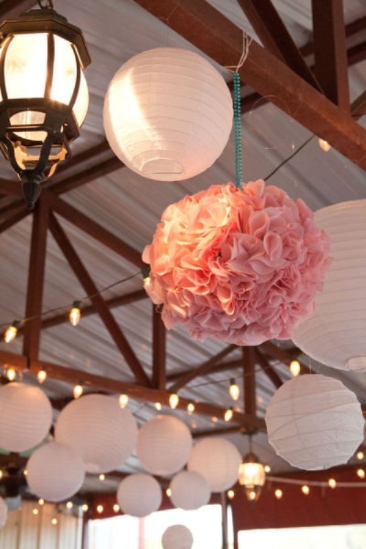 White paper lamps and pink paper pompoms plus lights for simple and cozy wedding reception decor