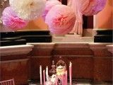 pink and white paper pompoms over the table match the colors and make the space look chic and romantic