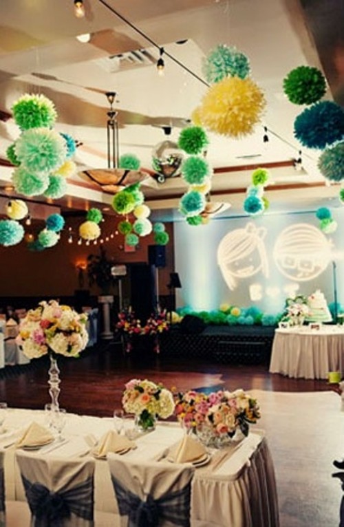 green and yellow paper pompom garlands over the reception space make it look bold and fun