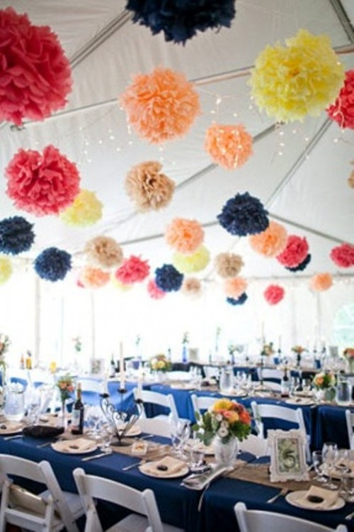 colorful paper pompom garlands over the reception space make it look more fun and add a relaxed feel to it