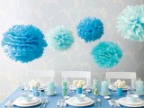 light blue and bold blue paper pompoms over the table accent its blue decor and add an ethereal feel here
