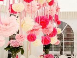 an overhead installation with pink, fuchsia and white paper pompoms and matching pink blooms on the table for a romantic feel