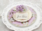 a beautiful lilac place setting with floral print plates and a charger plus a teacup with lilac inside