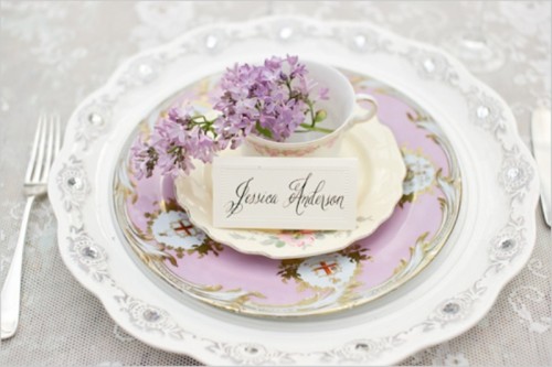 a beautiful lilac place setting with floral print plates and a charger plus a teacup with lilac inside