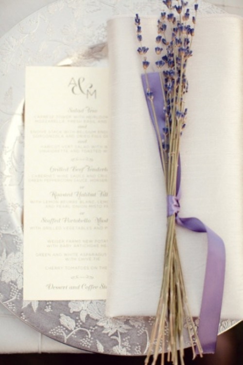 a silver floral print charger, a menu, a napkin and some lavender with lilac ribbon for a chic place setting