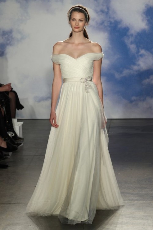 a romantic off the shoulder a-line wedding dress with a draped bodice and a tulle skirt plus an embellished sash is all cool