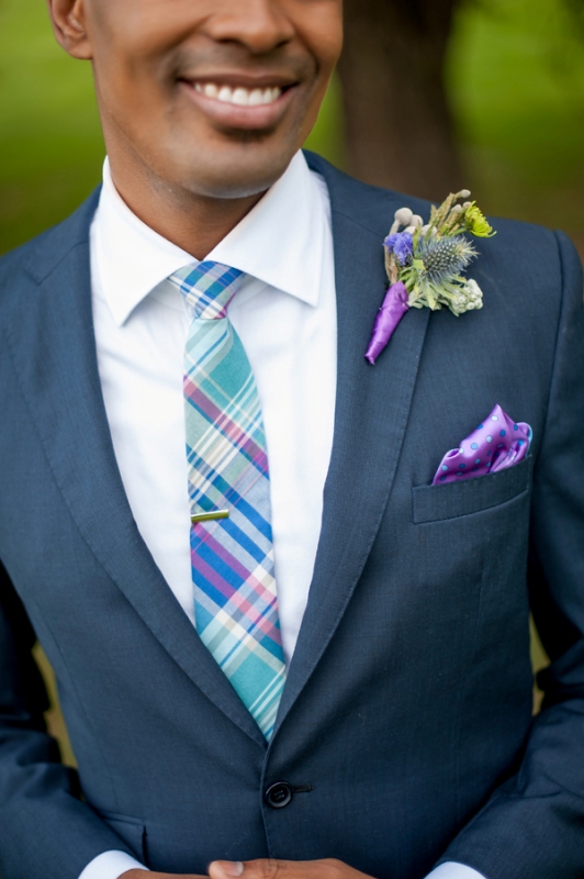 A bold blue, purple and mint printed tie, a purple pocket square and a green boutonniere with a purple wrap