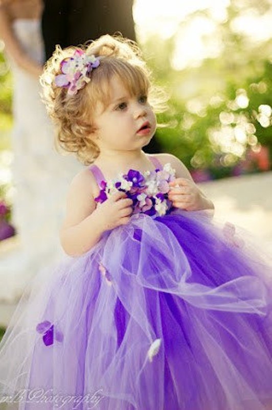 A purple flower girl dress of tulle and with a floral bodice plus a purple floral crown is super cute and bright