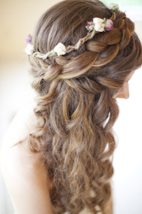 long wavy hair with a braided halo and neutral and bright blooms as a crown on top is a lovely idea for a beach or some other wedding, a rustic or a boho one