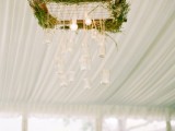 a unique woodland wedding chandelier of a wooden frame, greenery and hanging bulbs and jars